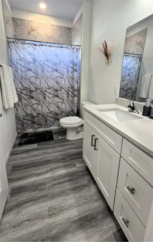 a bathroom with a granite countertop toilet sink and mirror