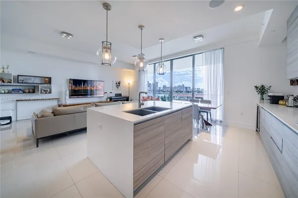 a large kitchen with kitchen island a large counter top space a sink a stove and a chandelier