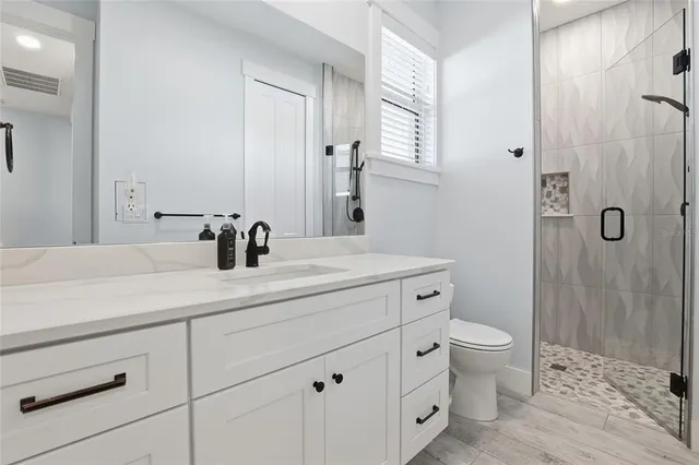 a bathroom with a granite countertop sink a toilet and shower