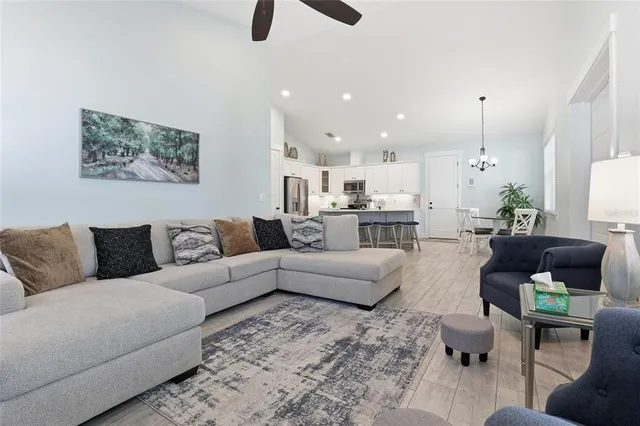 a living room with furniture kitchen view and a chandelier