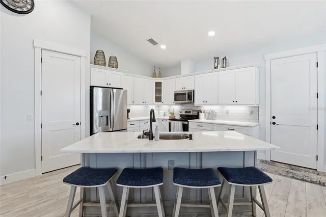 a large white kitchen with stainless steel appliances a table and chairs