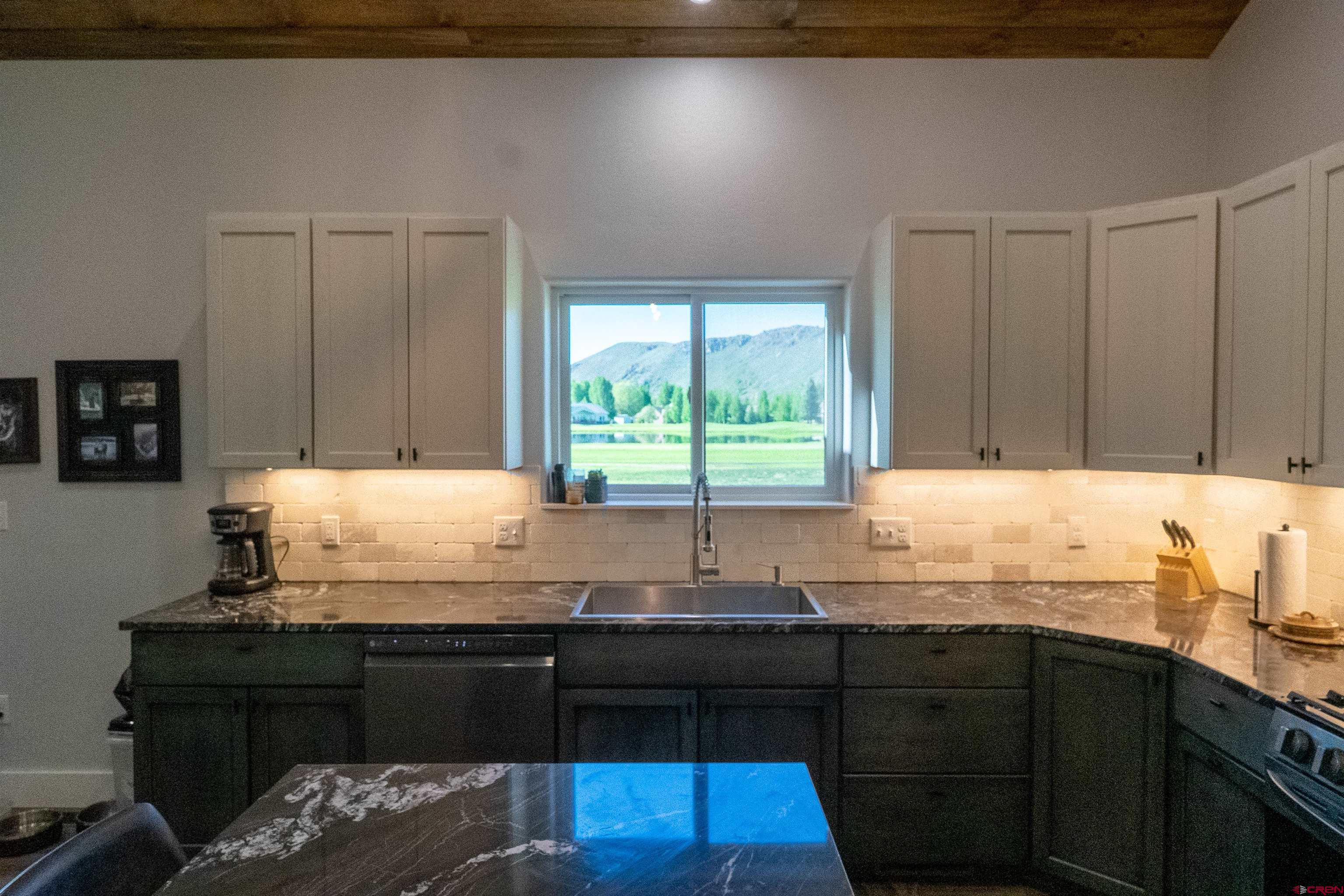 382 Tomichi Trail Gunnison, CO 81230 - Photo 15 of 34 a kitchen with granite countertop a sink a window and cabinets