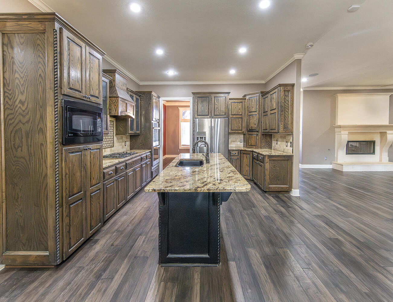 11302 Juneau Avenue Lubbock, TX 79424 - Photo 13 of 49 a kitchen with kitchen island granite countertop wooden floors and stainless steel appliances