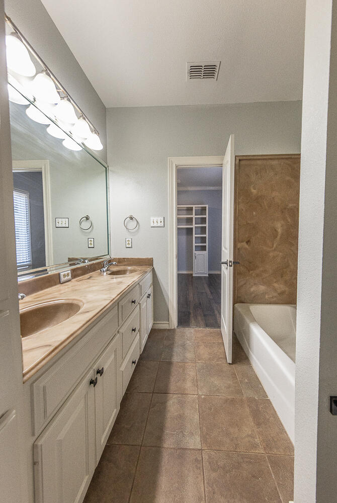 11302 Juneau Avenue Lubbock, TX 79424 - Photo 31 of 49 a spacious bathroom with a bathtub sink and mirror