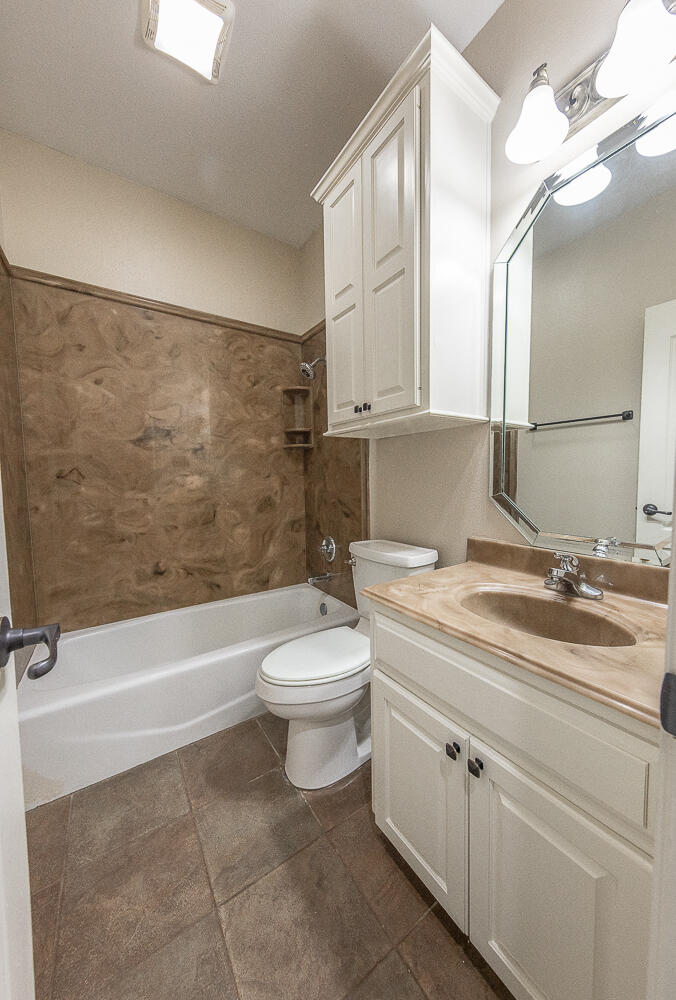11302 Juneau Avenue Lubbock, TX 79424 - Photo 34 of 49 a bathroom with a granite countertop toilet a sink and bathtub