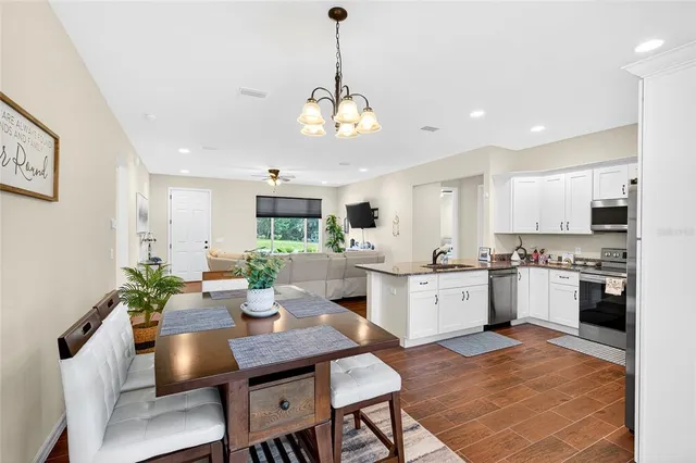 a kitchen with a dining table cabinets appliances and wooden floor