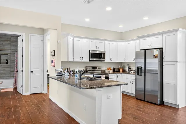 a kitchen with refrigerator a microwave a sink and cabinets