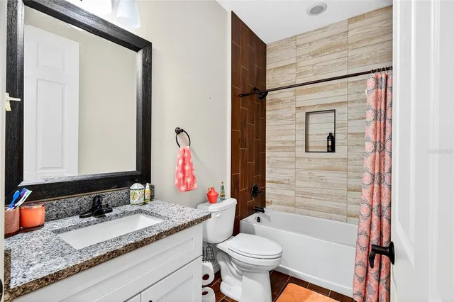 a bathroom with a granite countertop sink toilet mirror and bathtub