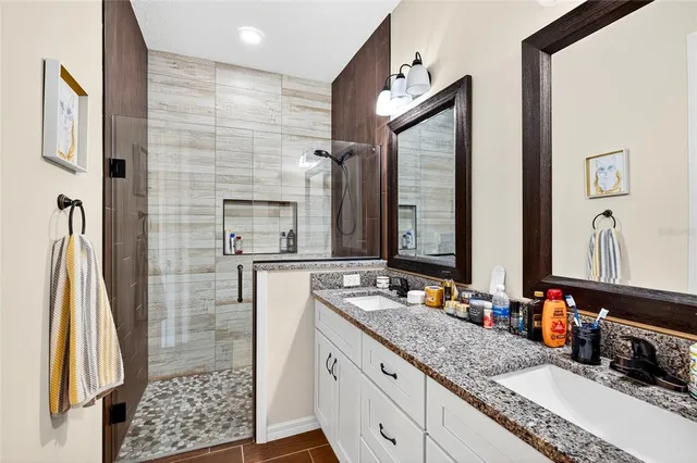 a bathroom with a granite countertop sink a mirror and shower