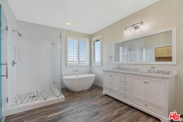 a spacious bathroom with double sink a mirror a window and a bathtub