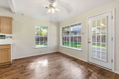 a view of an empty room with a window and wooden floor