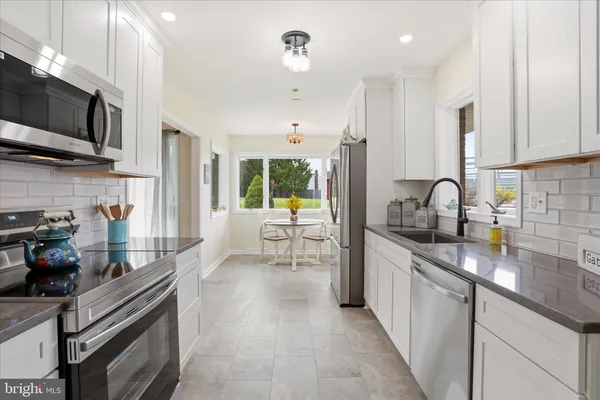 a kitchen with stainless steel appliances granite countertop a stove top oven a sink a dining table and chairs with wooden floor