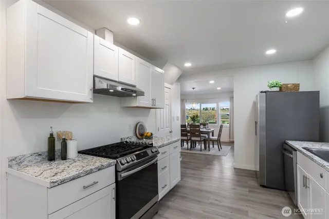 a kitchen with stainless steel appliances granite countertop a refrigerator and a stove top oven