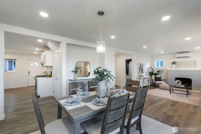 a kitchen with stainless steel appliances granite countertop a stove a refrigerator a sink a dining table and chairs with wooden floor