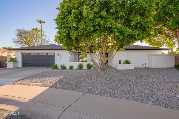 a front view of a house with a yard and a tree