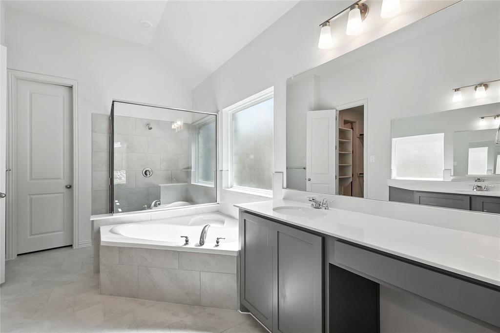 1434 Odette Drive Arlington, TX 76013 - Photo 22 of 38 Bathroom featuring a bath, vaulted ceiling, vanity, tiled shower, and a walk in closet