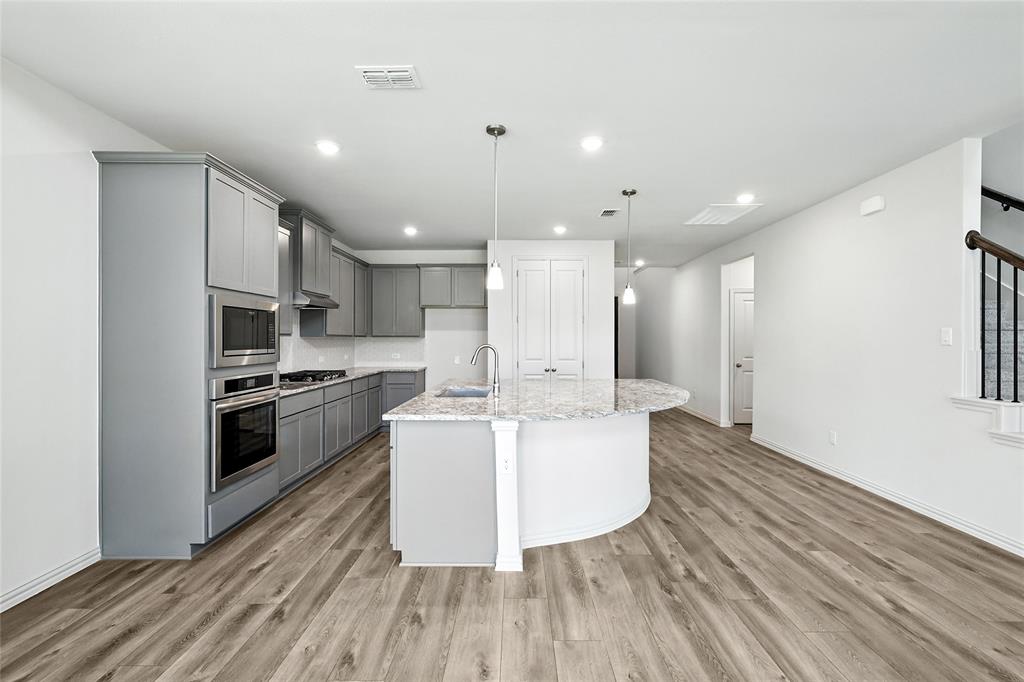 1434 Odette Drive Arlington, TX 76013 - Photo 9 of 38 Kitchen featuring gray cabinetry, appliances with stainless steel finishes, light wood-style floors, light stone countertops, and recessed lighting