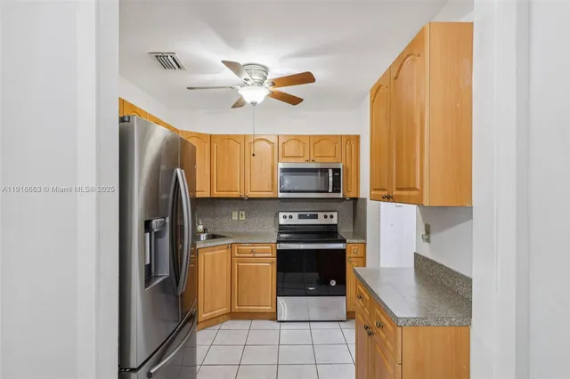a kitchen with stainless steel appliances granite countertop a refrigerator a stove and a sink with wooden floor