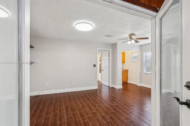 an empty room with wooden floor chandelier fan and windows