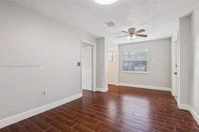 a view of empty room with wooden floor and window