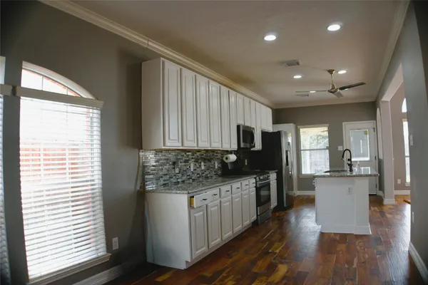 a kitchen with stainless steel appliances kitchen island granite countertop a stove a sink and a refrigerator