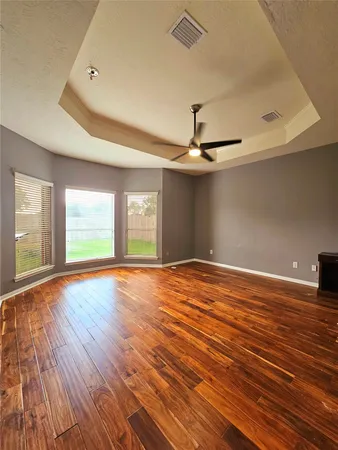 a view of empty room with wooden floor and fan