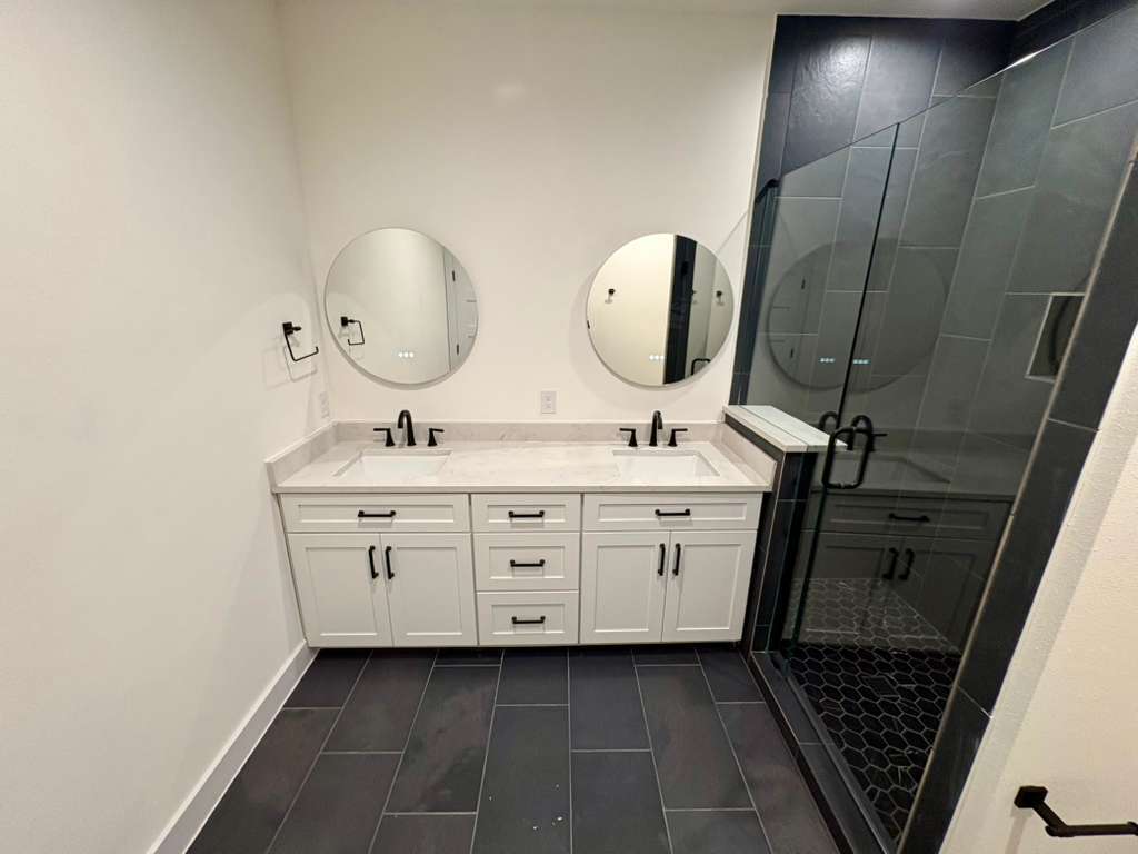 10209 Gail Road Austin, TX 78748 - Photo 22 of 38 Bathroom with a stall shower, double vanity, and dark tile patterned flooring