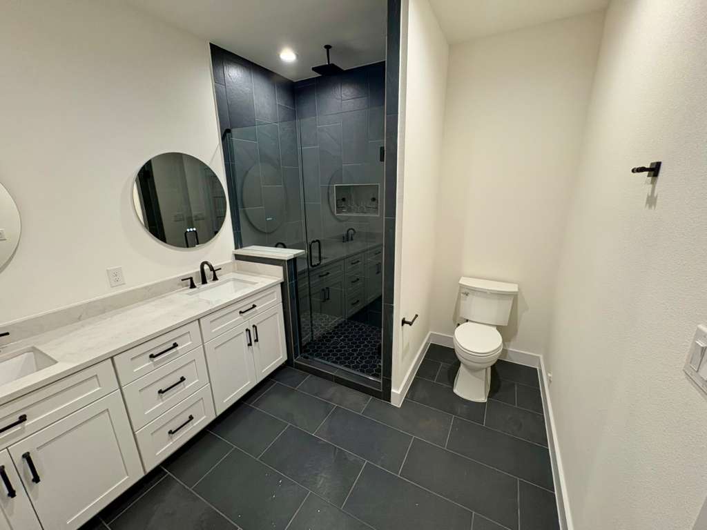 10209 Gail Road Austin, TX 78748 - Photo 23 of 38 Full bathroom featuring a shower stall, double vanity, dark tile patterned flooring, and recessed lighting