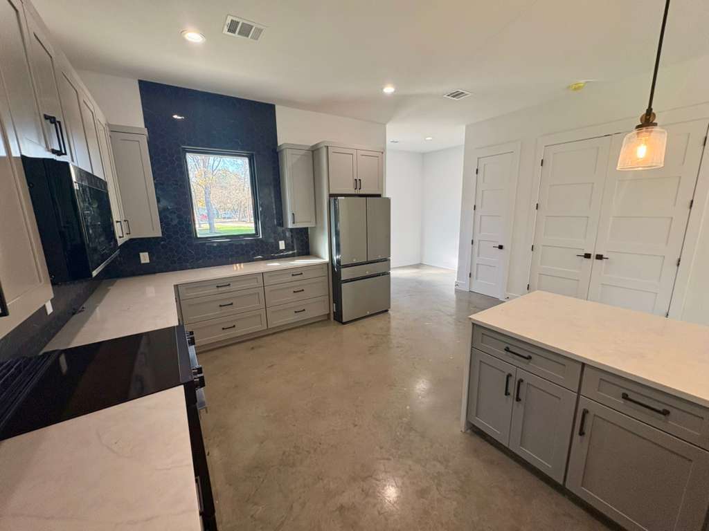 10209 Gail Road Austin, TX 78748 - Photo 9 of 38 Kitchen featuring gray cabinetry, black appliances, finished concrete floors, backsplash, and decorative light fixtures