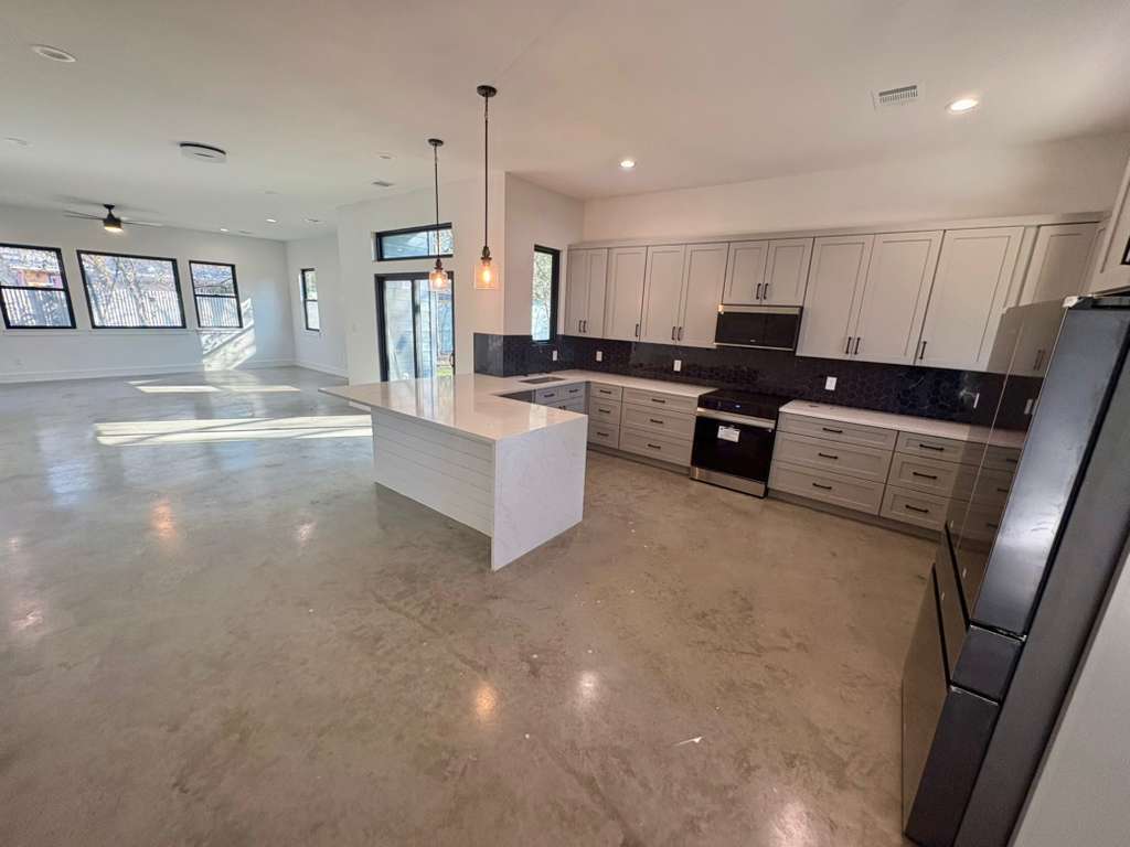 10209 Gail Road Austin, TX 78748 - Photo 37 of 38 Kitchen with open floor plan, freestanding refrigerator, light stone countertops, pendant lighting, and finished concrete floors