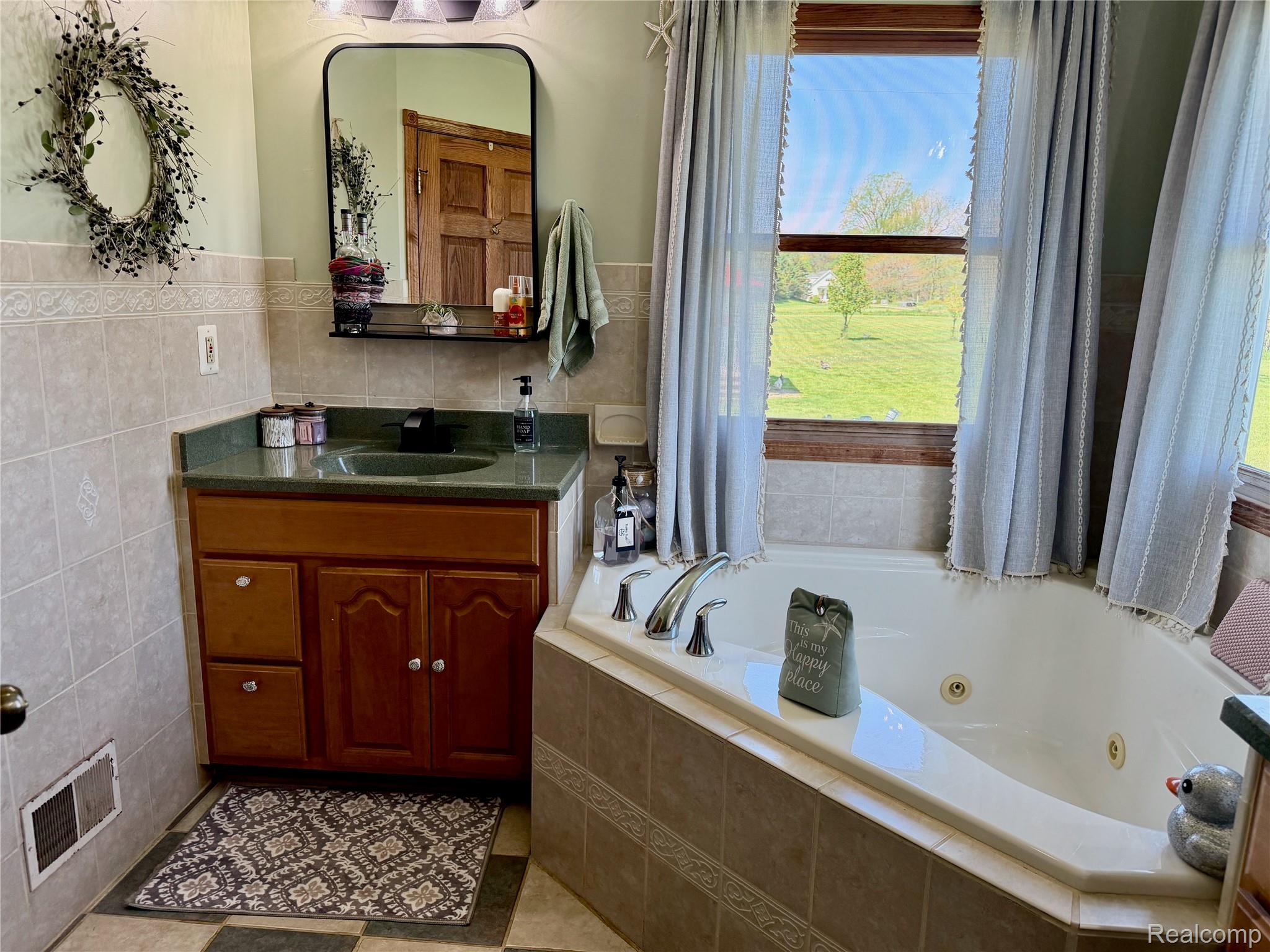 6860 Grand River Road Bancroft, MI 48414 - Photo 14 of 31 Bathroom featuring vanity, a tub with jets, tile walls, a wainscoted wall, and light tile patterned floors
