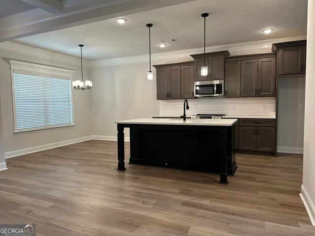 a kitchen with kitchen island stainless steel appliances a sink cabinets a sink and a wooden floor