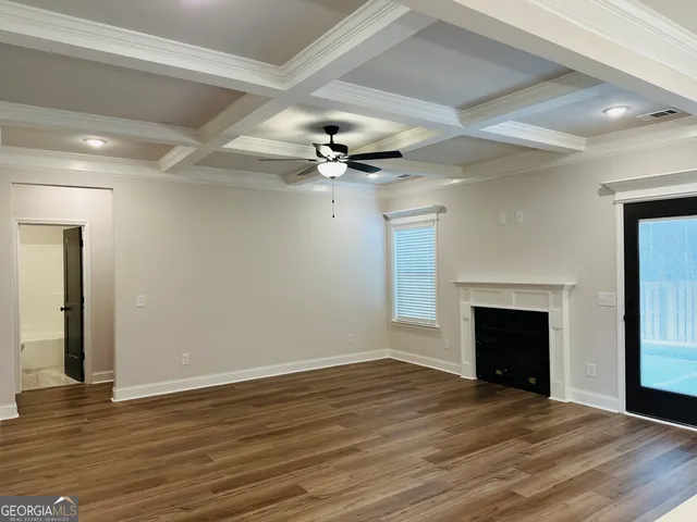 an empty room with wooden floor fireplace and fan