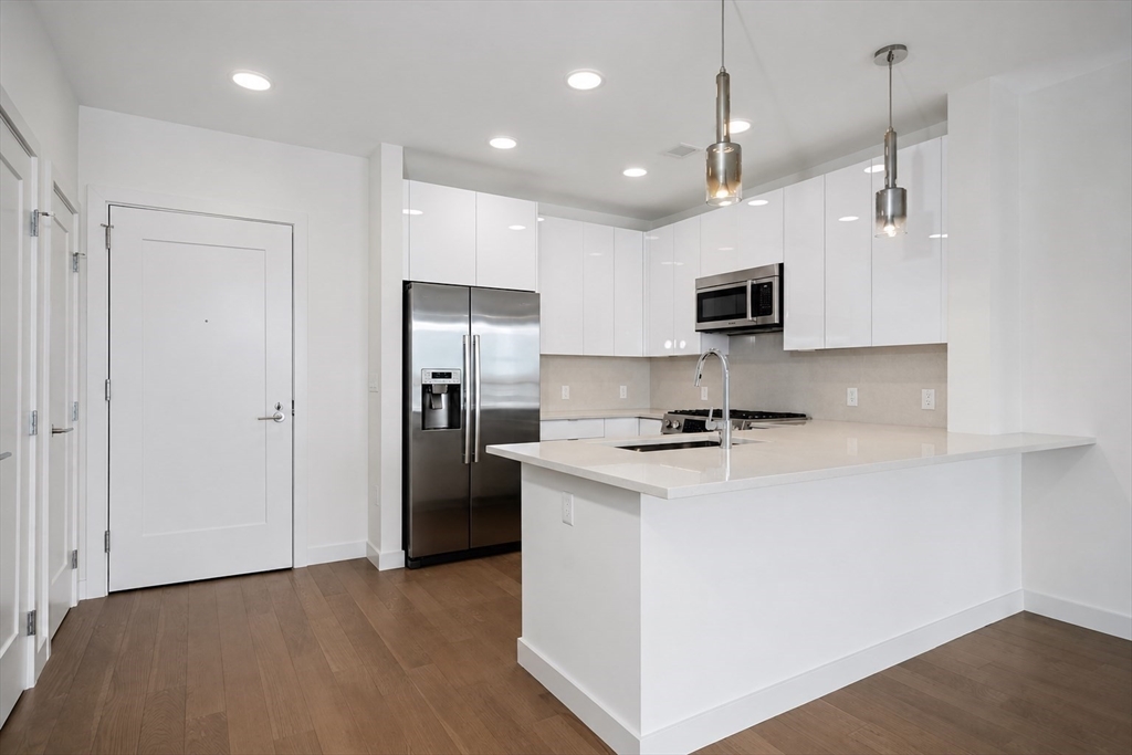 45 Lewis Street, Unit 312 Boston, MA 02128 - Photo 3 of 17 a kitchen with kitchen island a sink stainless steel appliances and cabinets