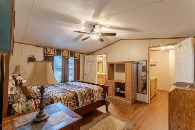 a bedroom with a bed ceiling fan and a wooden floor
