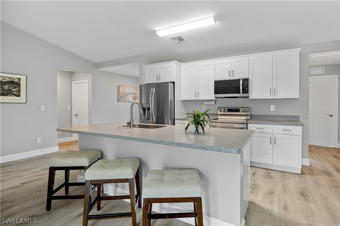 16582 Becasse Drive Punta Gorda, FL 33955 - Photo 7 of 32 a kitchen with stainless steel appliances a dining table chairs microwave and sink