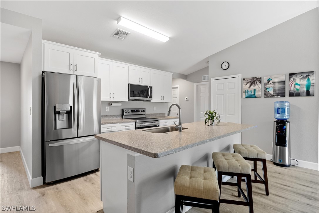 16582 Becasse Drive Punta Gorda, FL 33955 - Photo 8 of 32 a kitchen with a refrigerator a stove a sink dishwasher and wooden cabinets with wooden floor
