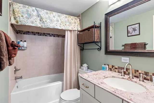 a bathroom with a granite countertop sink mirror toilet and bathtub