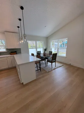 an empty room with wooden floor ceiling fan and windows