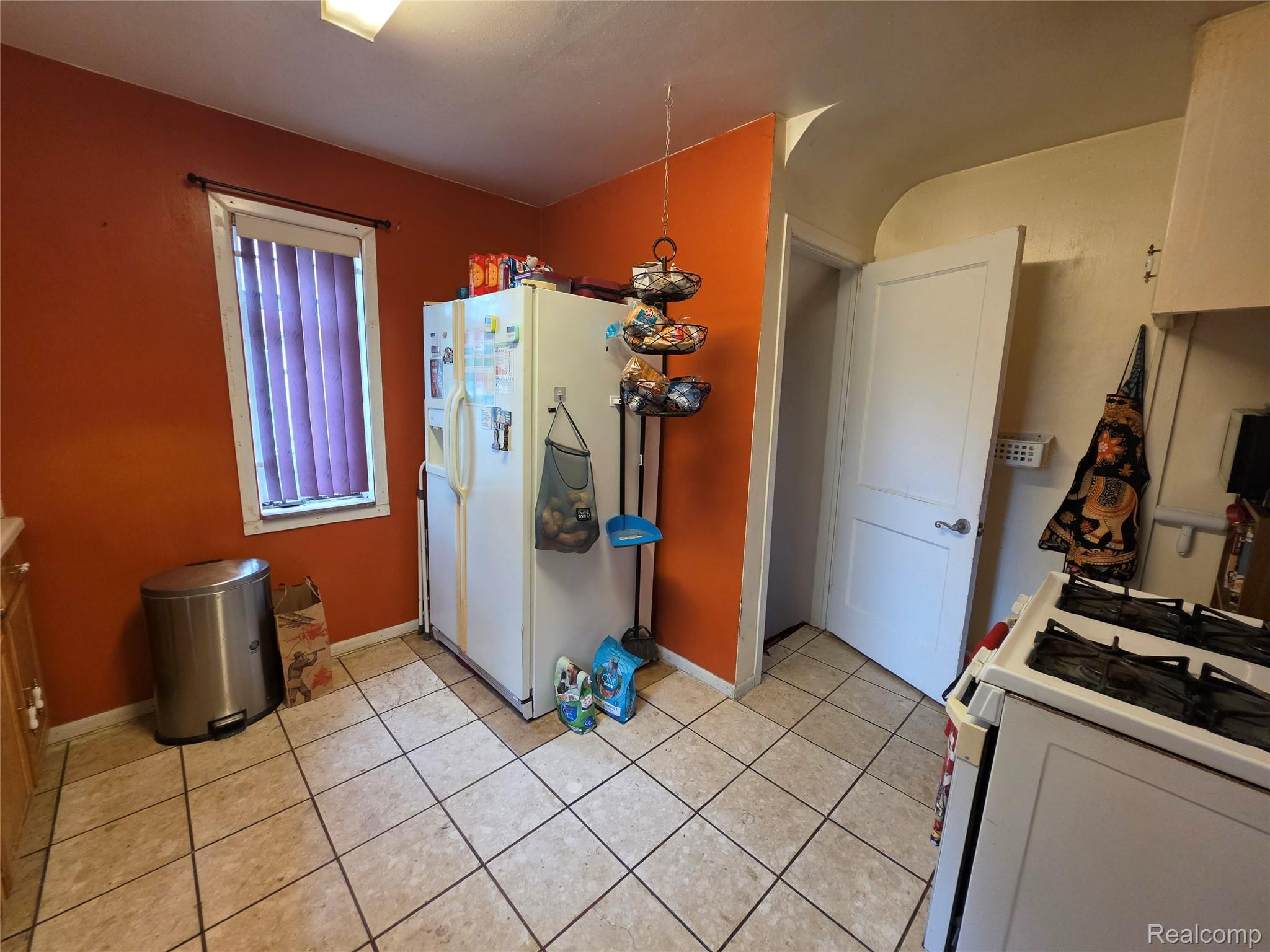 15832 Griggs Street Detroit, MI 48238 - Photo 12 of 24 Kitchen space with tiled flooring, a window featuring vertical blinds, and a white paneled door