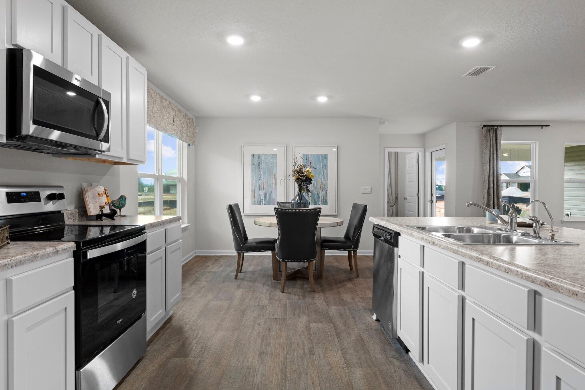 9318 Tara Circle Milton, FL 32583 - Photo 7 of 30 a kitchen with stainless steel appliances granite countertop a stove a sink a microwave and wooden floors