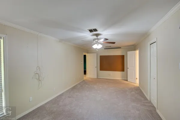 a view of an empty room with a chandelier fan