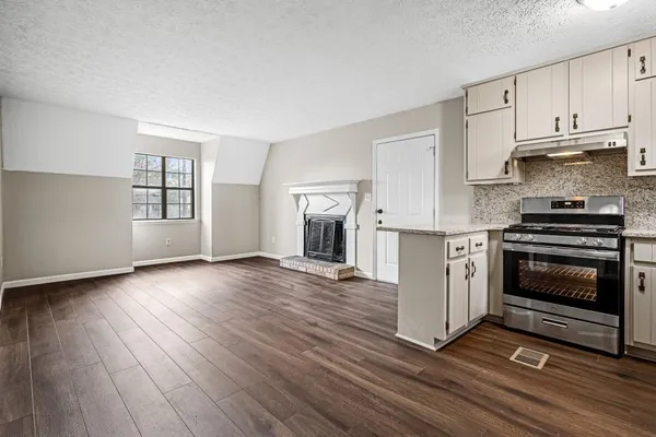 an empty room with wooden floor fireplace and windows