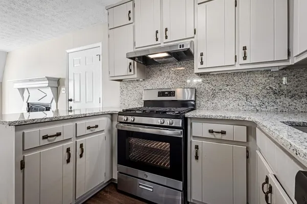 a kitchen with granite countertop white cabinets and white appliances