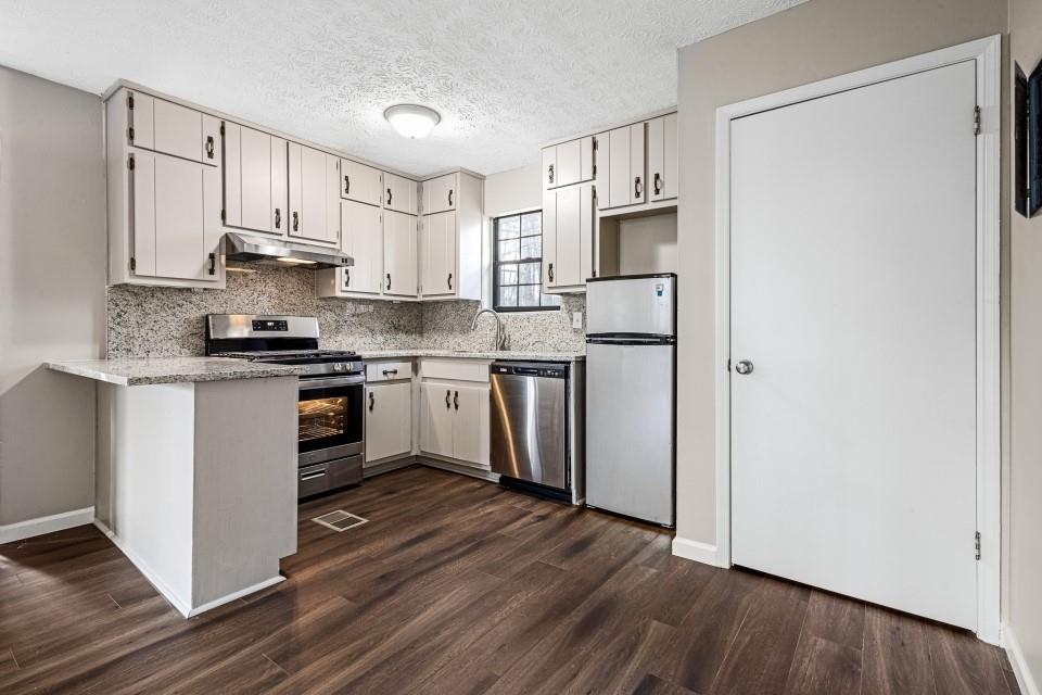 2037 Laboon Circle Atlanta, GA 30349 - Photo 10 of 18 a kitchen with stainless steel appliances granite countertop a refrigerator a stove top oven a sink and dishwasher with wooden floor