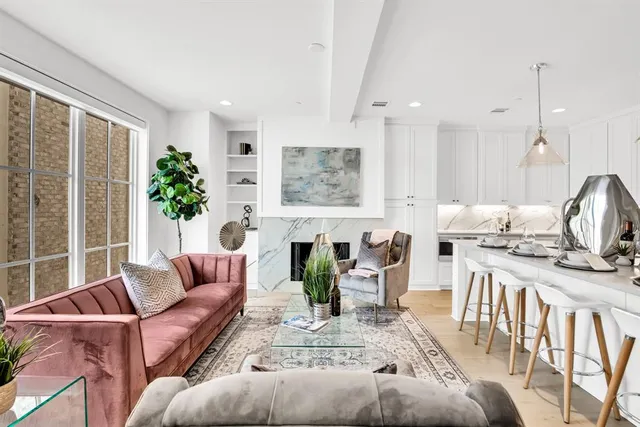 a living room with furniture a fireplace a potted plant and a large window