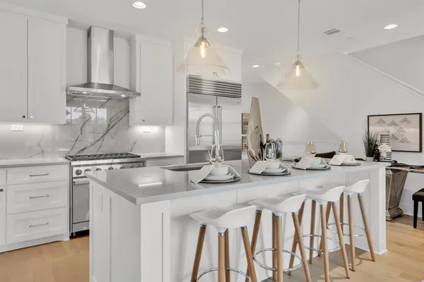 a kitchen with kitchen island granite countertop a table chairs sink and cabinets