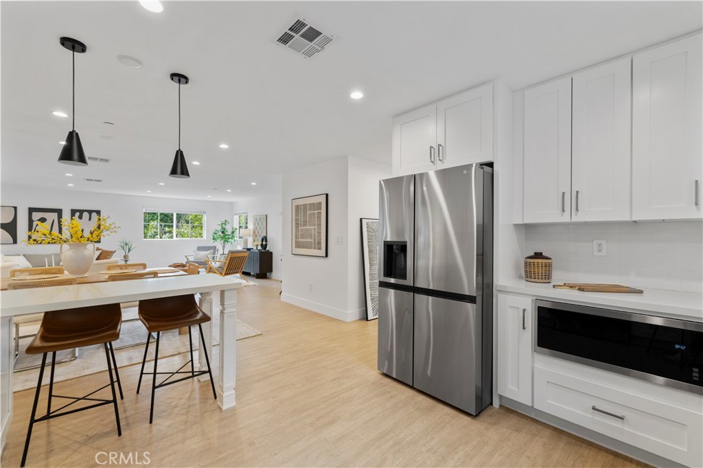 5248 Segals Way Sherman Oaks, CA 91411 - Photo 11 of 37 a kitchen with stainless steel appliances kitchen island granite countertop a refrigerator a stove a sink dishwasher and white cabinets with wooden floor