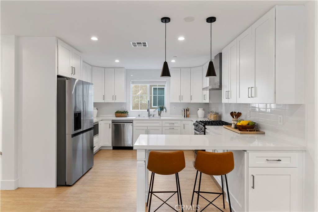 5248 Segals Way Sherman Oaks, CA 91411 - Photo 8 of 37 a kitchen with stainless steel appliances granite countertop a refrigerator a sink dishwasher a stove and white cabinets with wooden floor