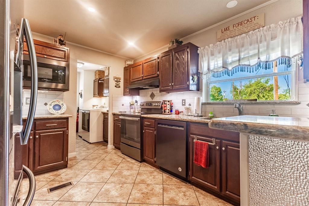 1167 Willow Road Graford, TX 76449 - Photo 13 of 33 a kitchen with stainless steel appliances granite countertop a stove a sink and a refrigerator